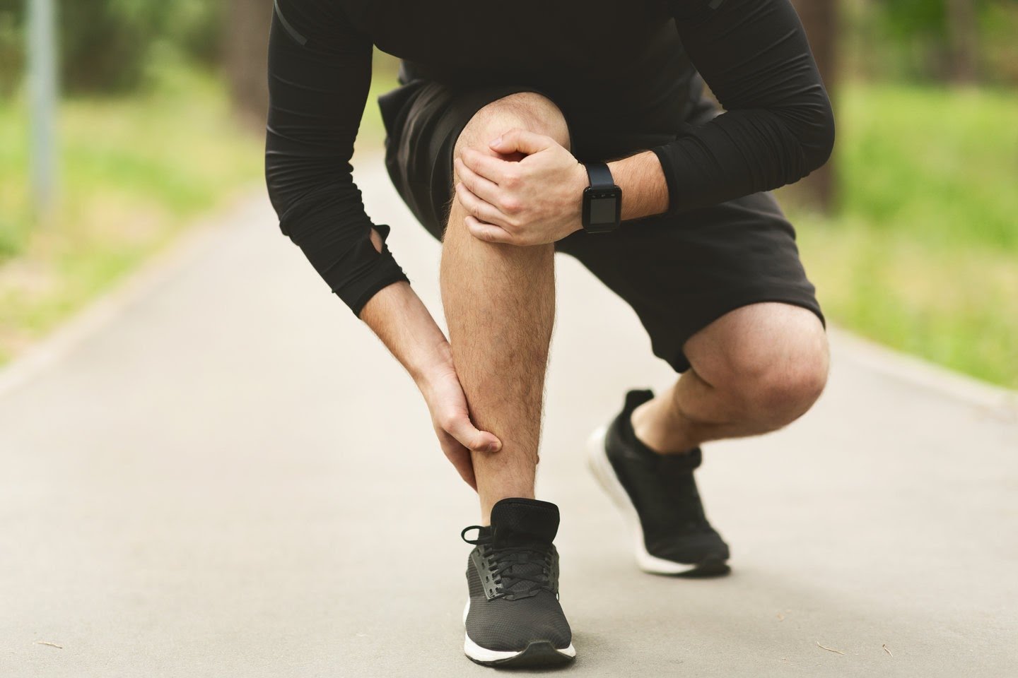 Young male runner is suffering from ankle pain on jogging, free space